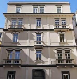 A multi-story building with a symmetrical facade, featuring evenly spaced windows and balconies on each floor. - Albergo Palazzo Decumani (Naples)