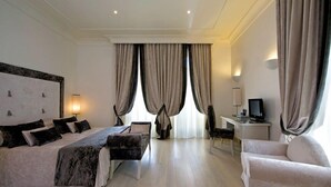 A hotel room with a large bed, a desk with a computer, a chair, and a TV. - Albergo Palazzo Decumani (Naples)