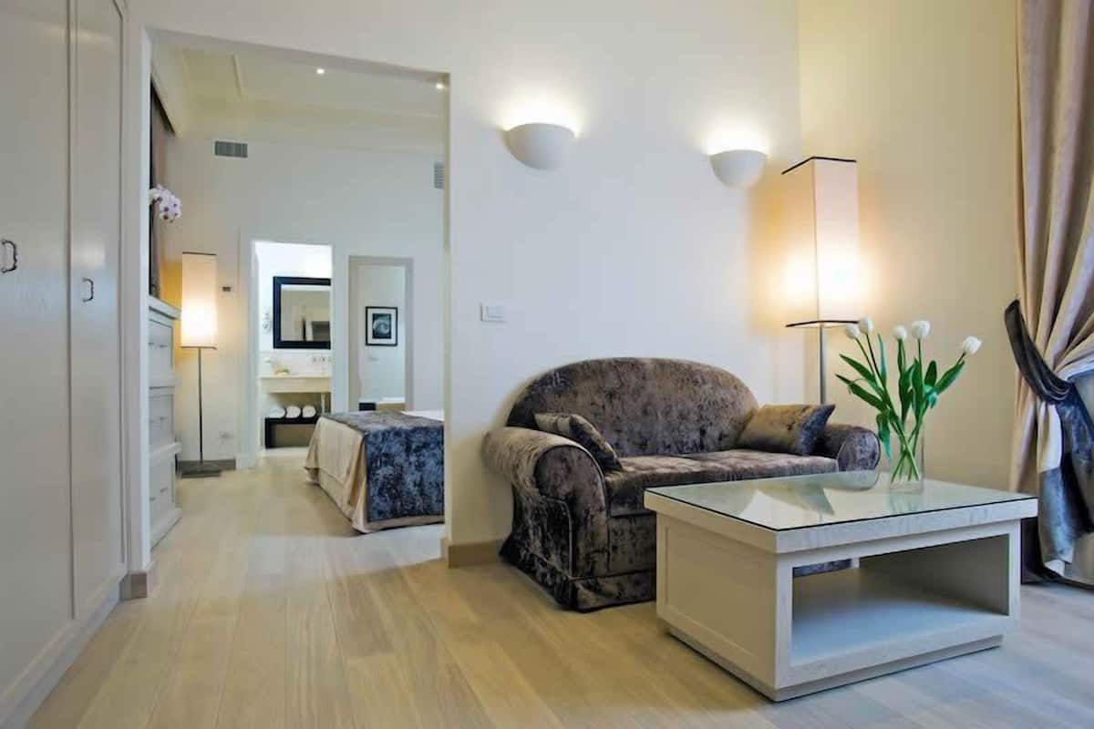 A modern living room with a sofa, a glass coffee table, and a lamp.