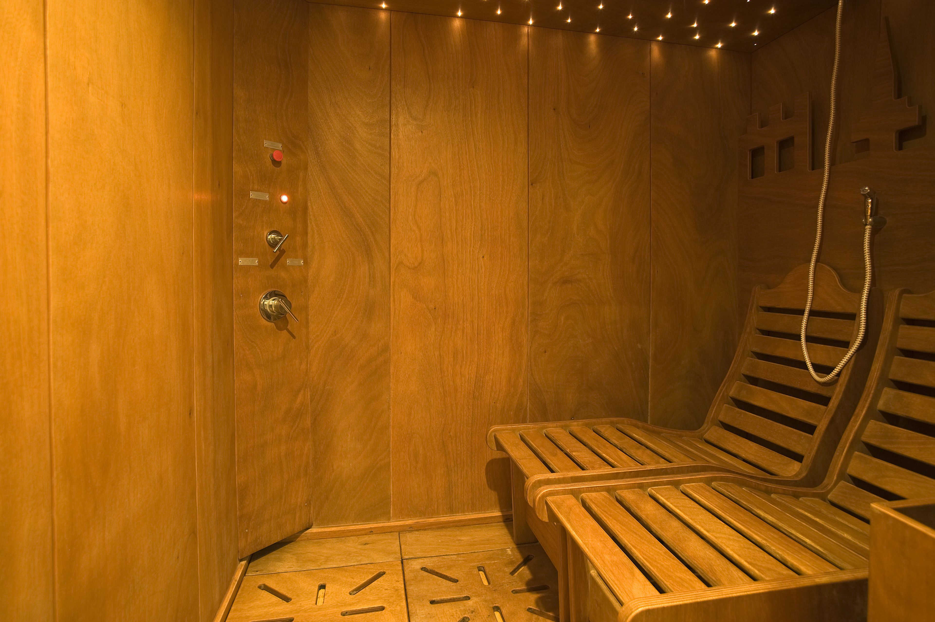 A wooden sauna with benches and a shower head.
