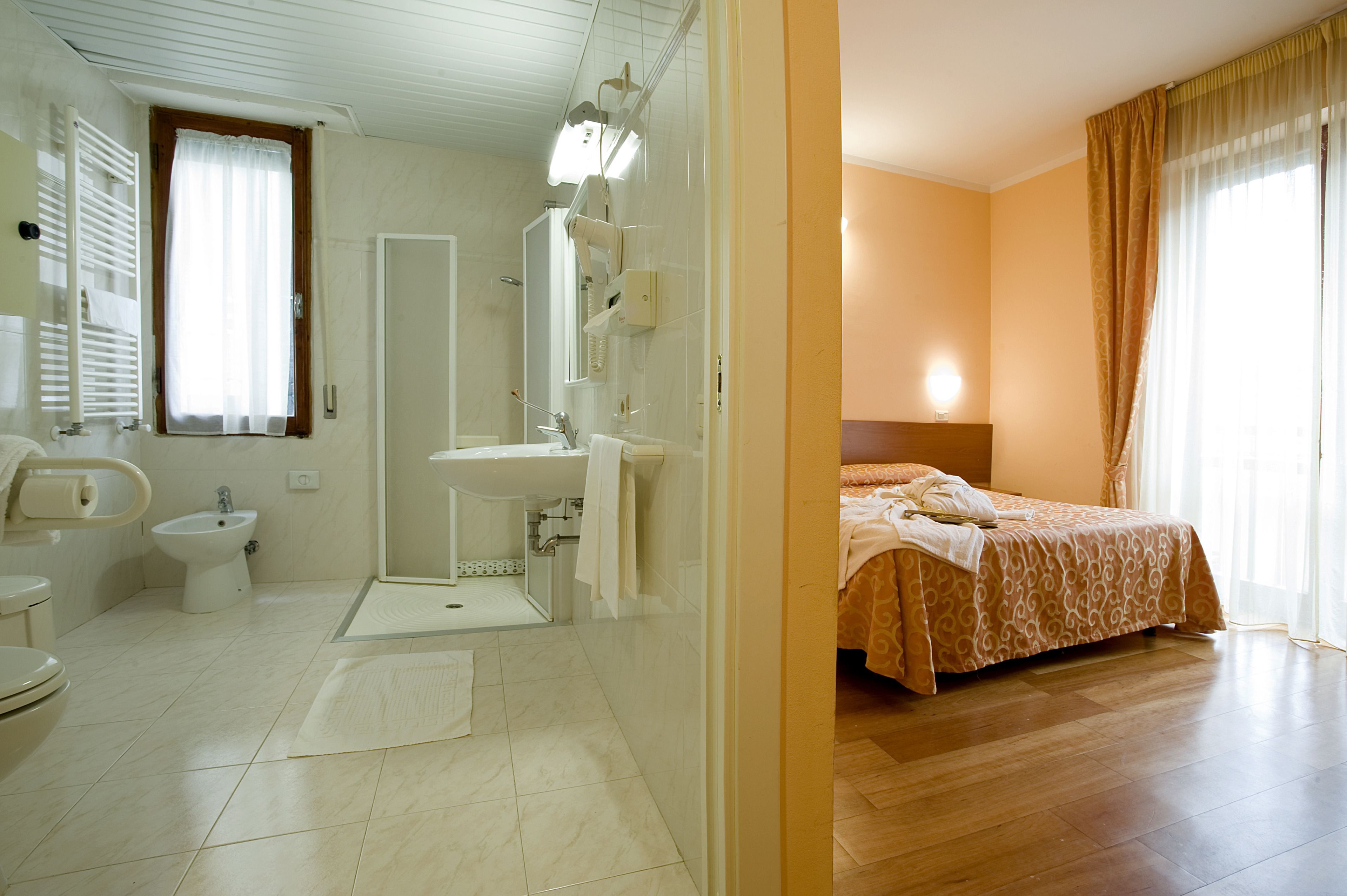 A hotel bathroom with a shower, sink, and toilet.