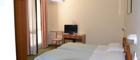 Una habitación de hotel con una cama, un escritorio con televisor y una ventana con cortinas.