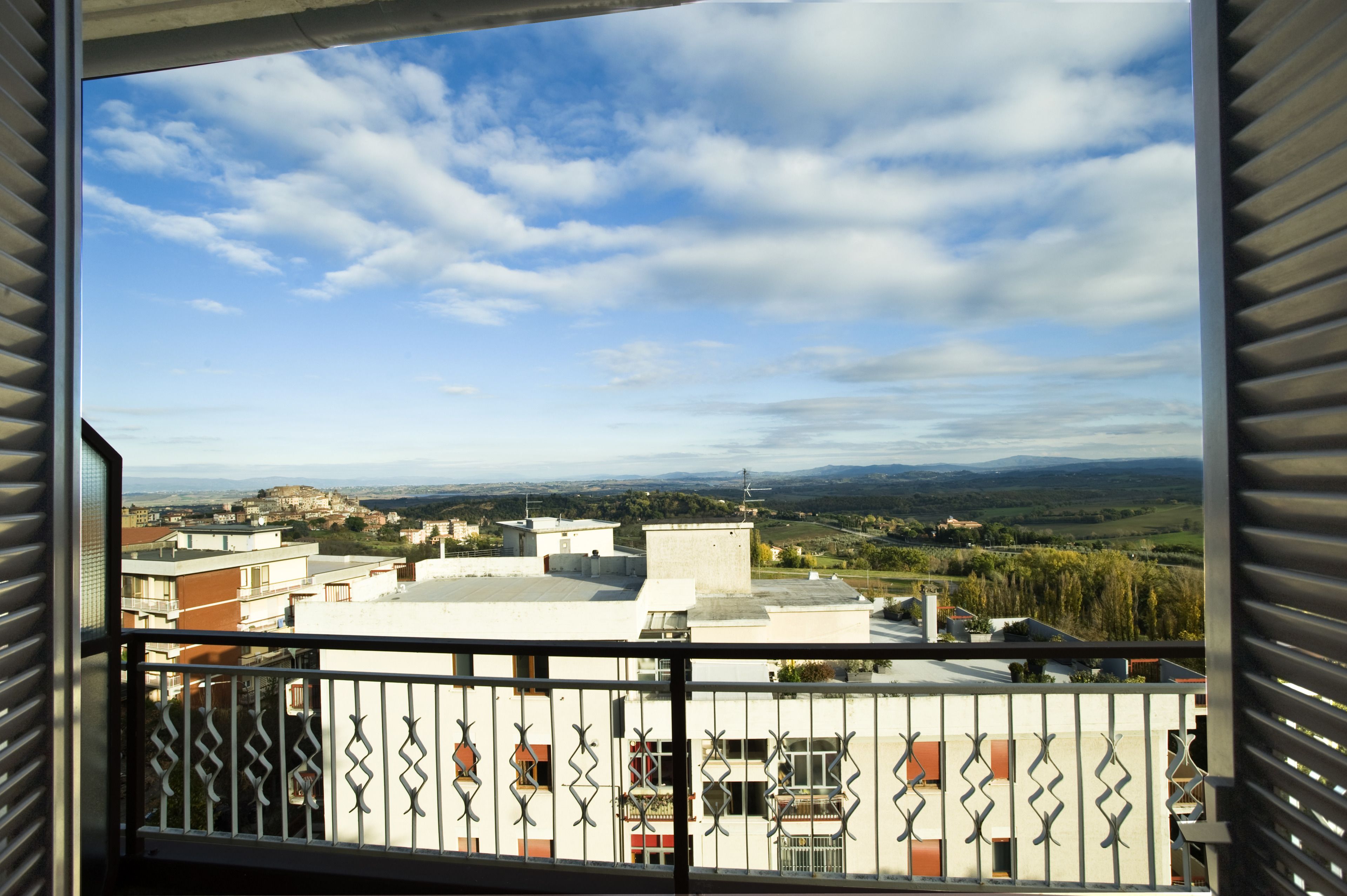 A balcony with a view of a town and distant mountains.