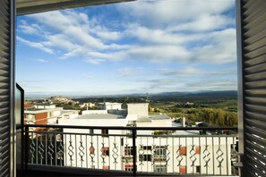 A balcony with a view of a town and distant mountains.