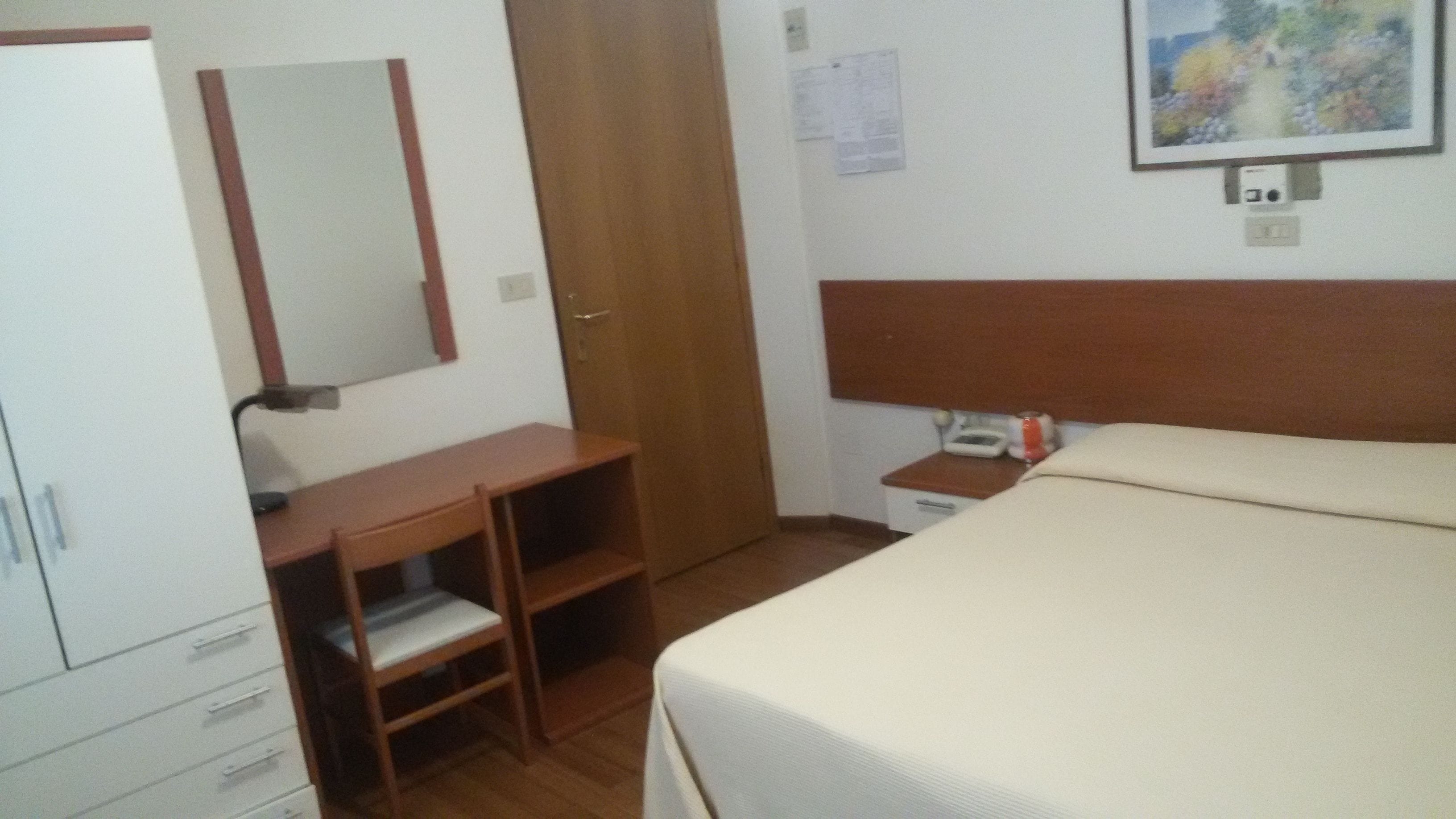Una camera da letto con un letto, una scrivania, una sedia, un armadio e un comodino.