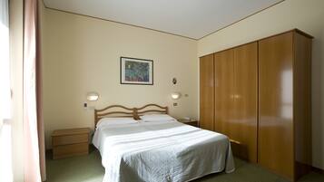 Een slaapkamer met een bed, nachtkastjes, een kledingkast en een schilderij aan de muur.