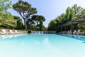 Une piscine avec des chaises longues blanches et un espace abrité.