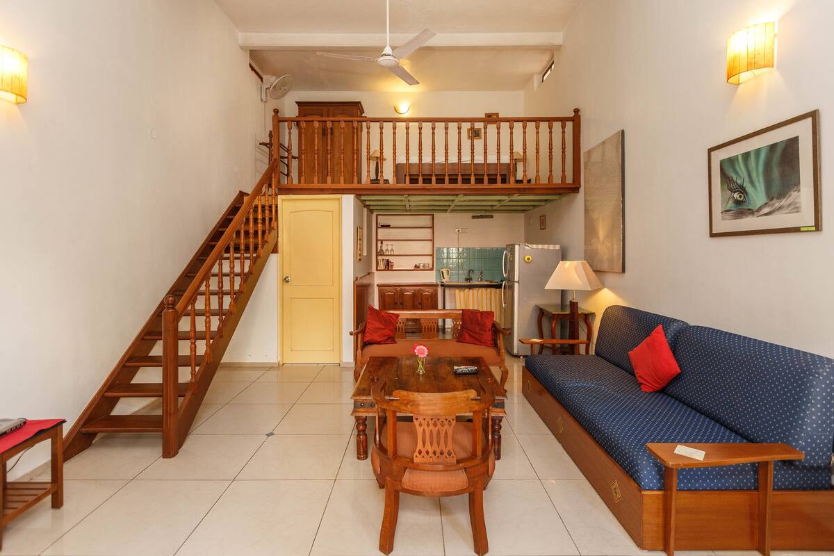 A spacious living area with a wooden staircase, a dining table, and a sofa.