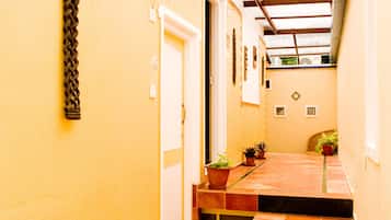 A narrow hallway with yellow walls, a tiled floor, and a staircase leading to an upper level.