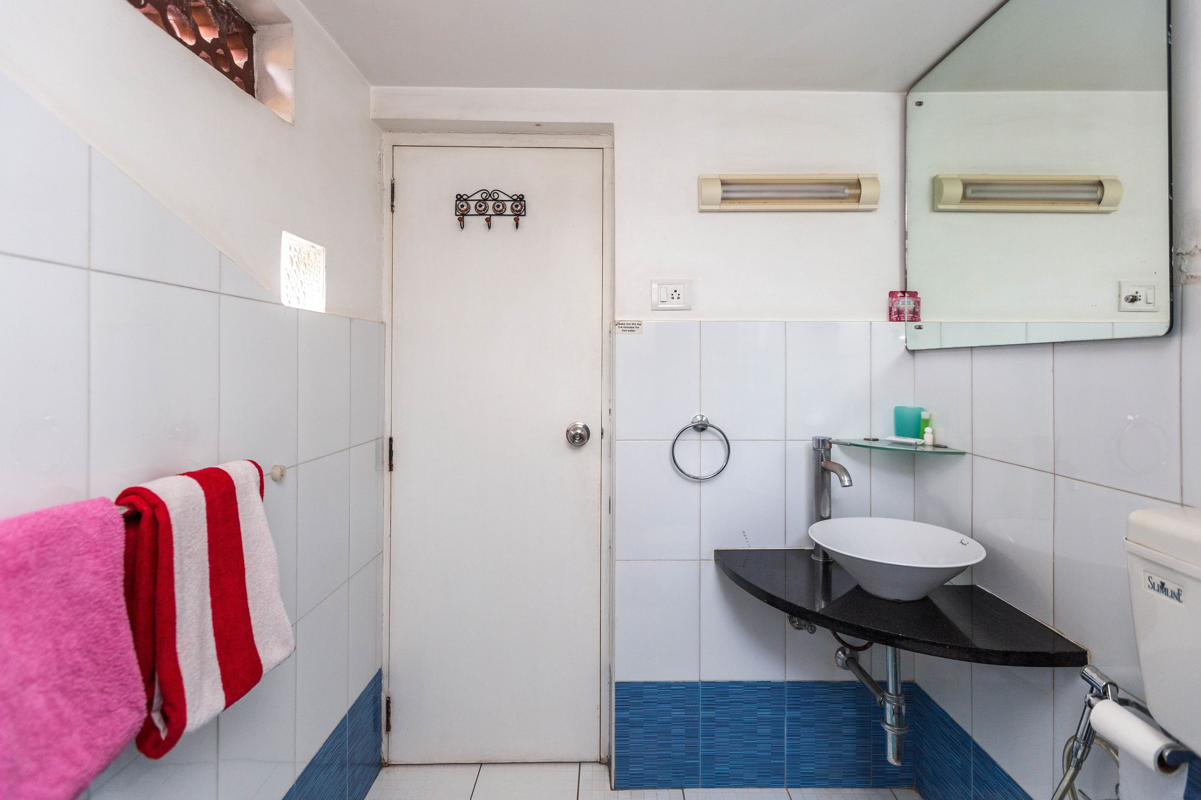 Un baño con una puerta blanca, un lavamanos con encimera negra y un espejo sobre el lavamanos.