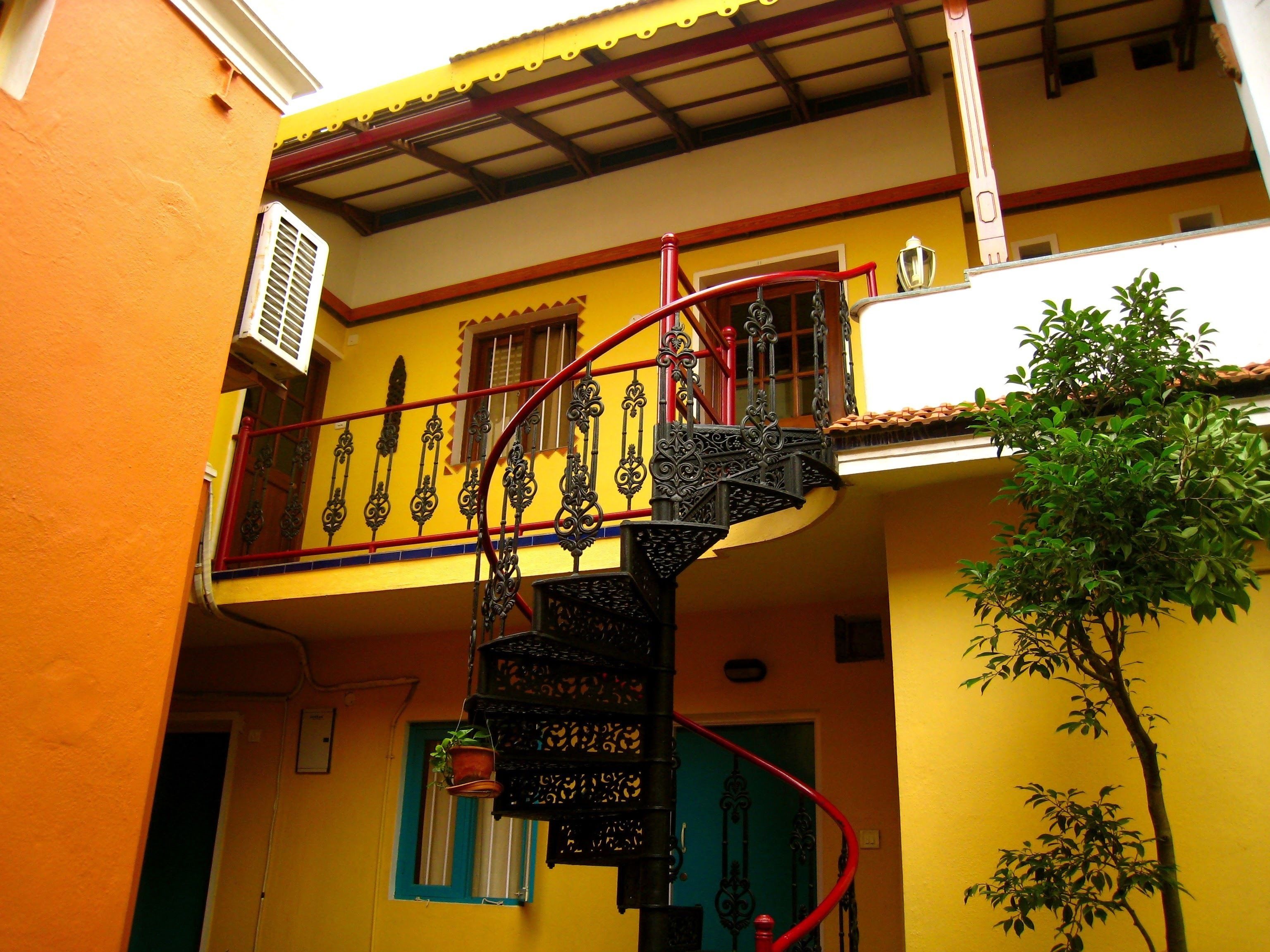 Un edificio amarillo con una escalera espiral roja y un balcón.