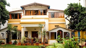 A two-story house with a balcony, potted plants, and a well-maintained lawn.