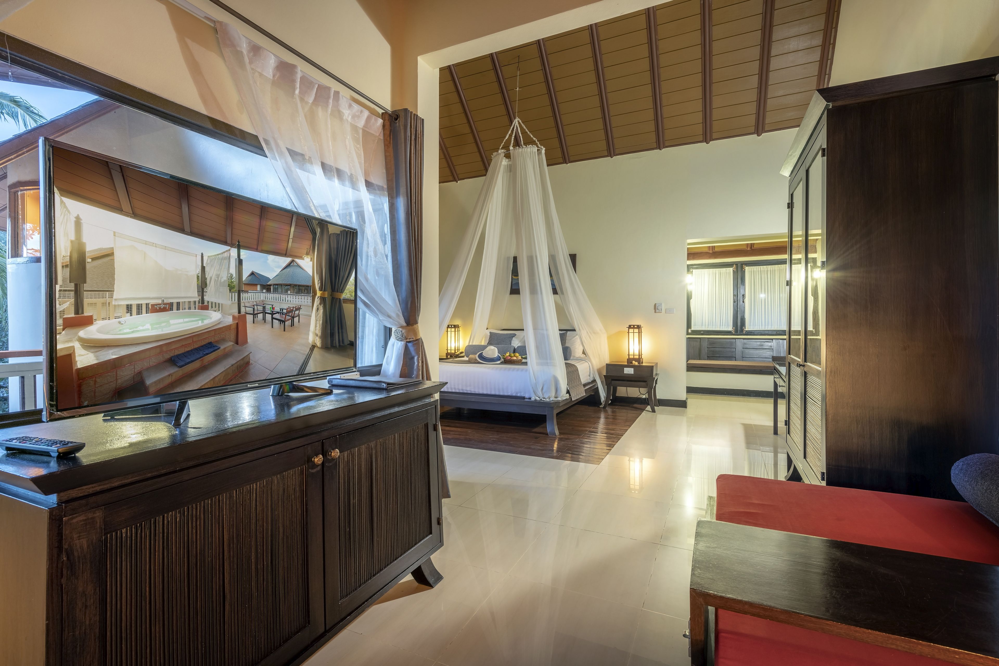 A spacious bedroom with a large bed, a canopy, and a view of a pool area.