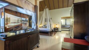 A spacious bedroom with a large bed, a canopy, and a view of a pool area.