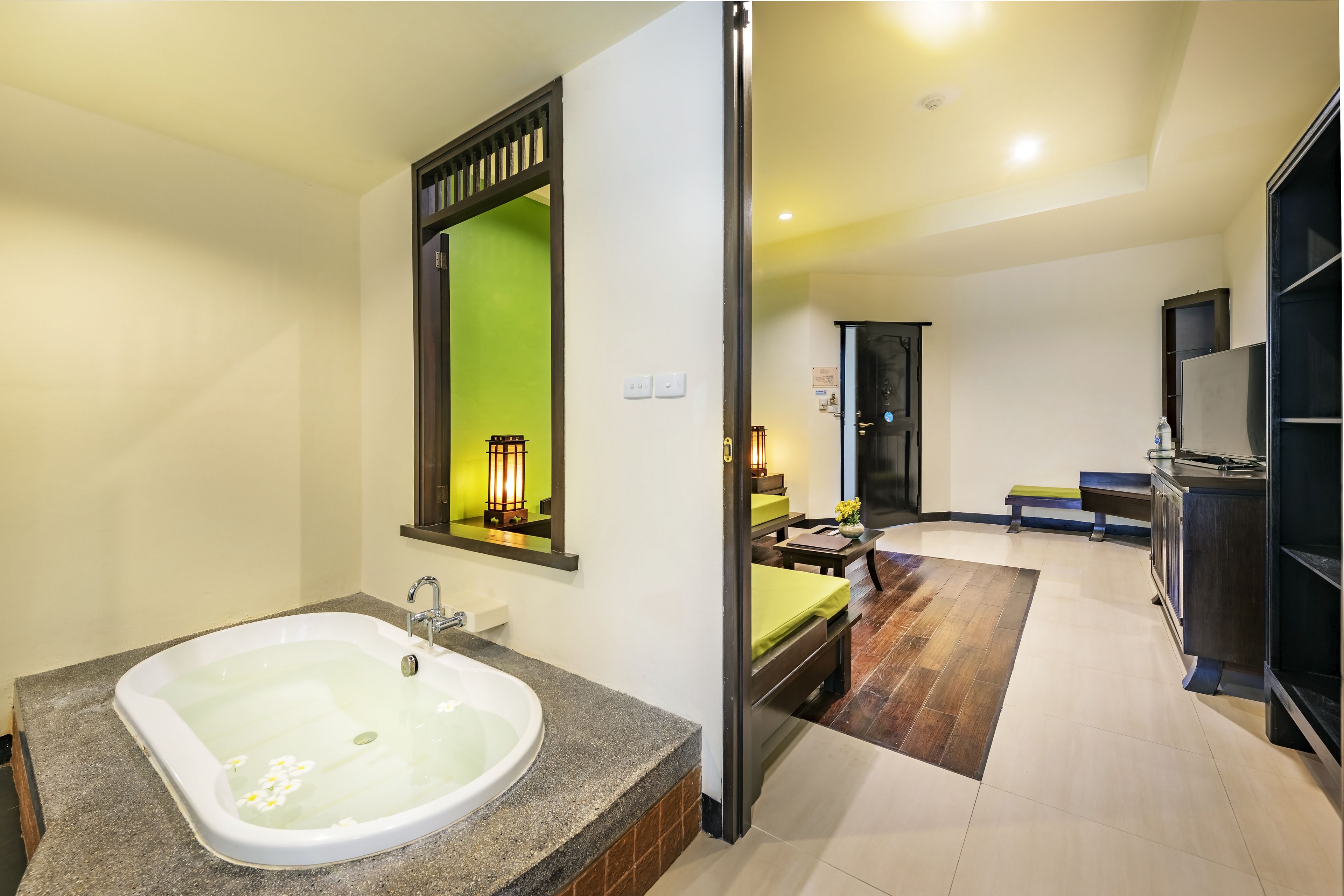 Un baño moderno con una bañera grande, un espejo y una pared verde.