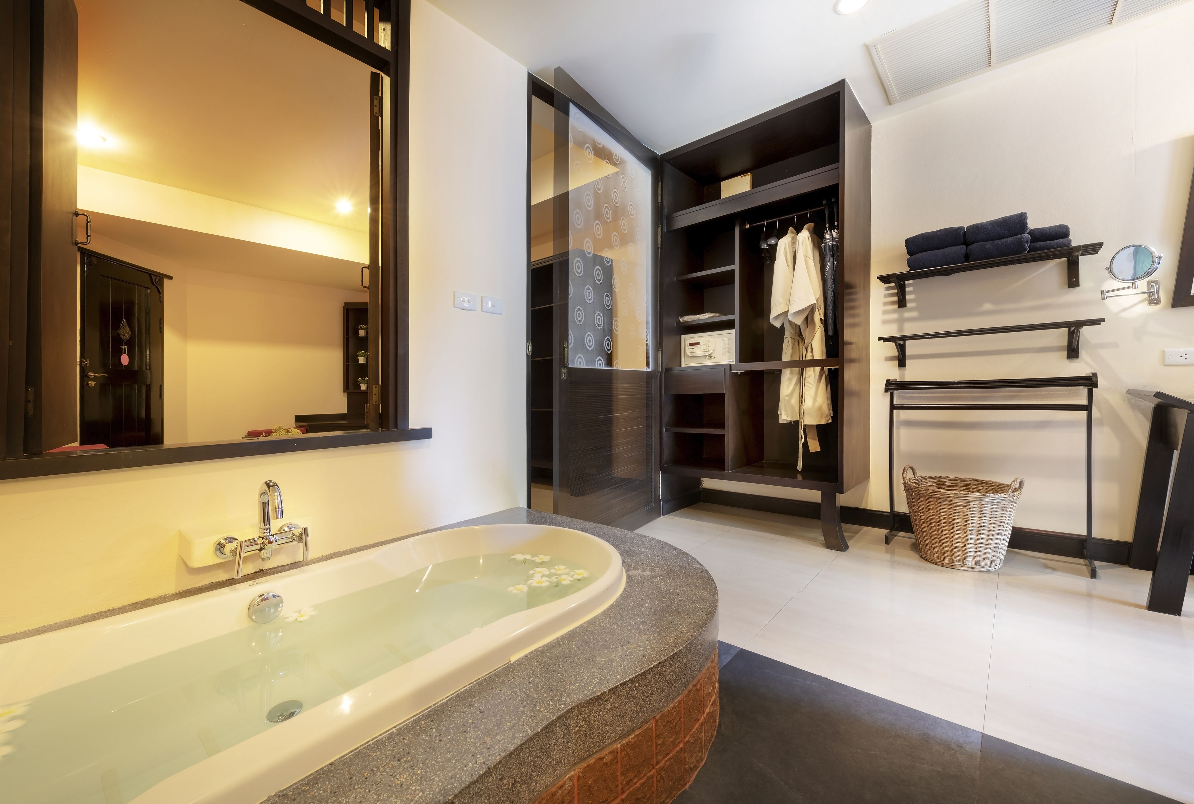 Une salle de bain moderne avec une baignoire sur pieds, un grand miroir et un dressing avec des étagères et un espace pour suspendre les vêtements.
