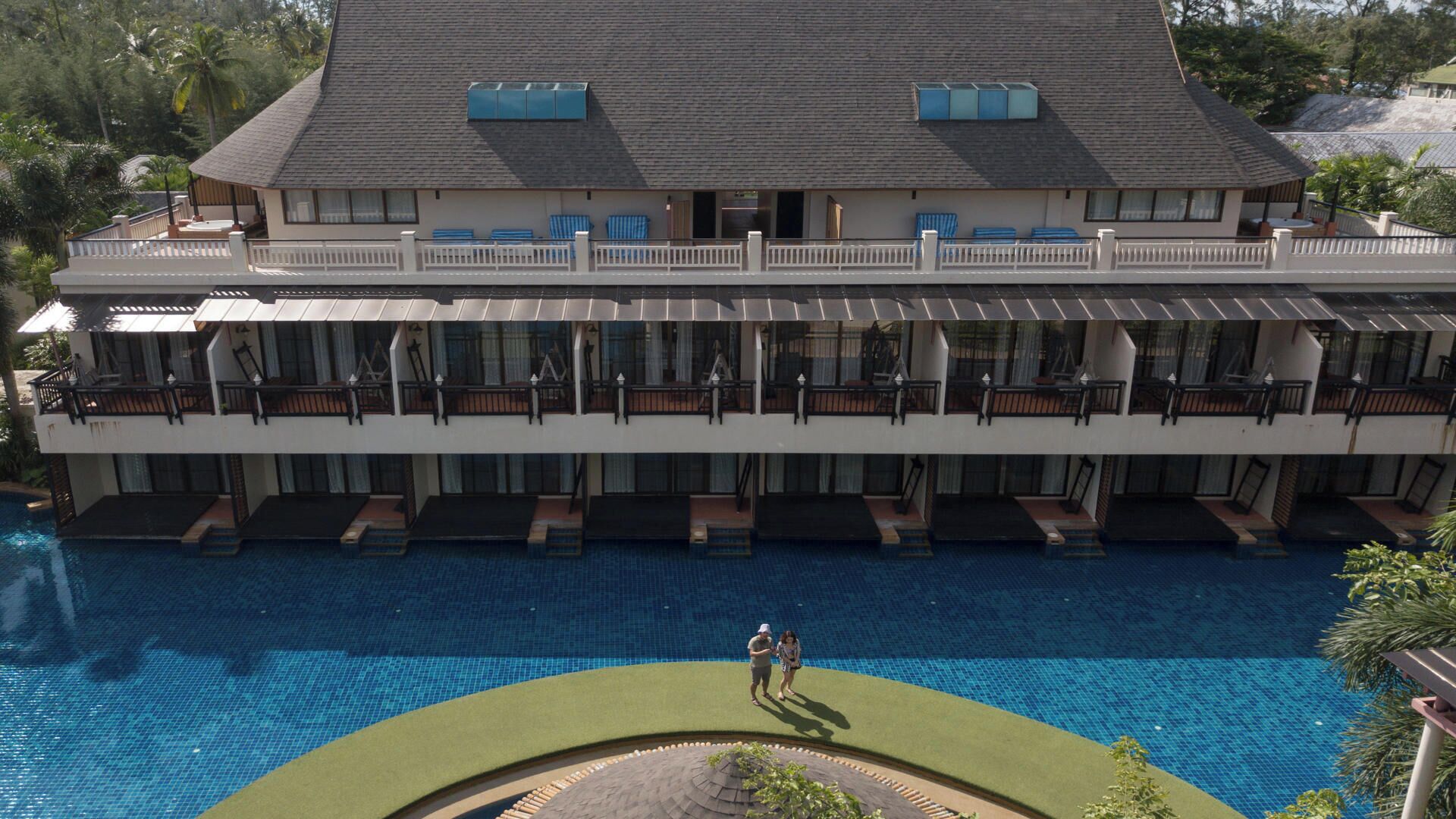 A large hotel with multiple balconies overlooking a swimming pool.