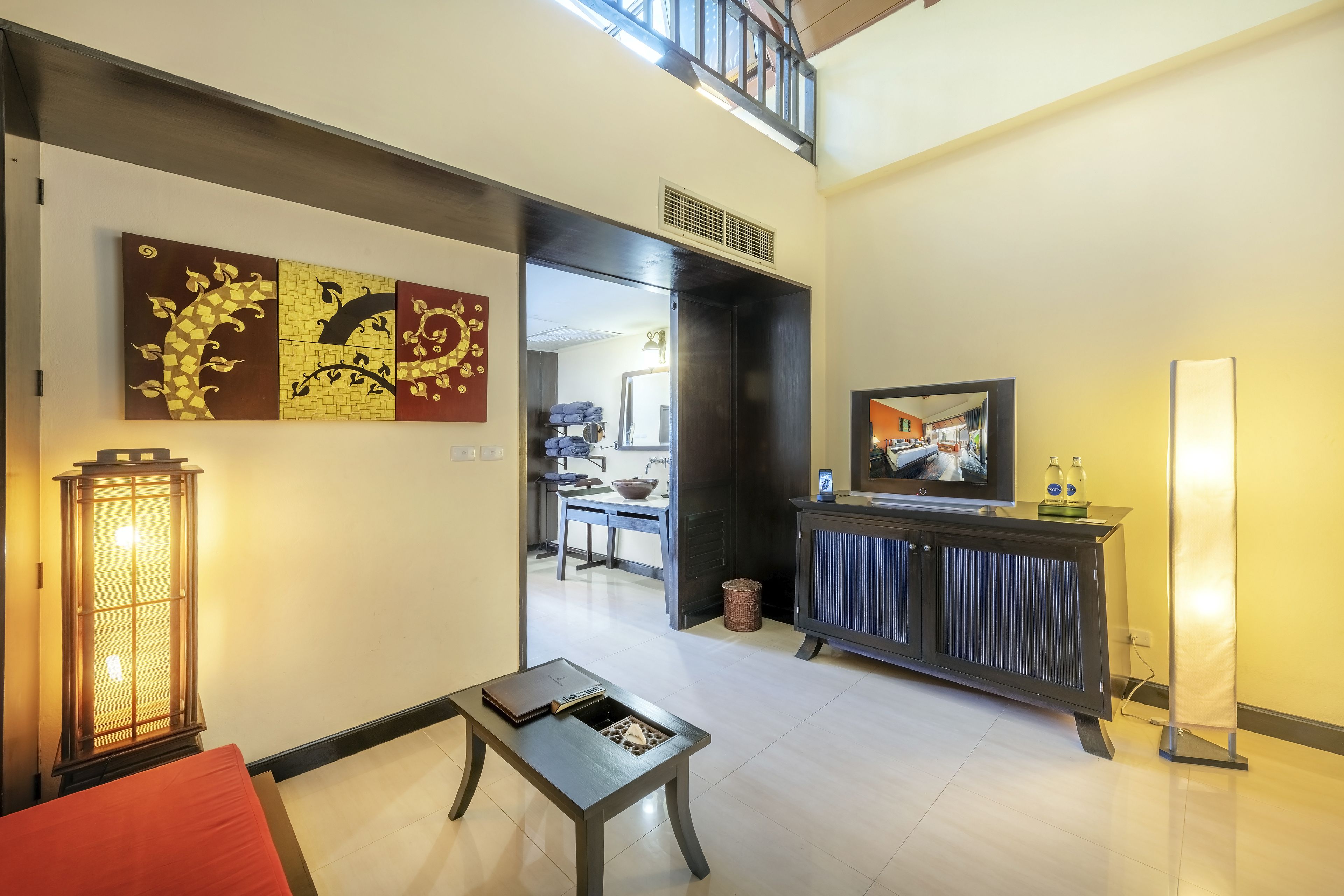 Amplia sala de estar con diseño moderno, que incluye un mueble de entretenimiento en tonos oscuros, un televisor de pantalla plana grande y una lámpara de pie de estilo clásico.