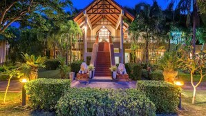 A hotel with a prominent staircase leading to the entrance, surrounded by well-maintained hedges and palm trees. - Chada Lanta Beach Resort  (Ko Lanta)