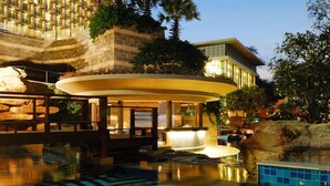 A modern hotel with a pool area featuring a circular water feature and a stone facade. - The Zign Hotel (Pattaya)