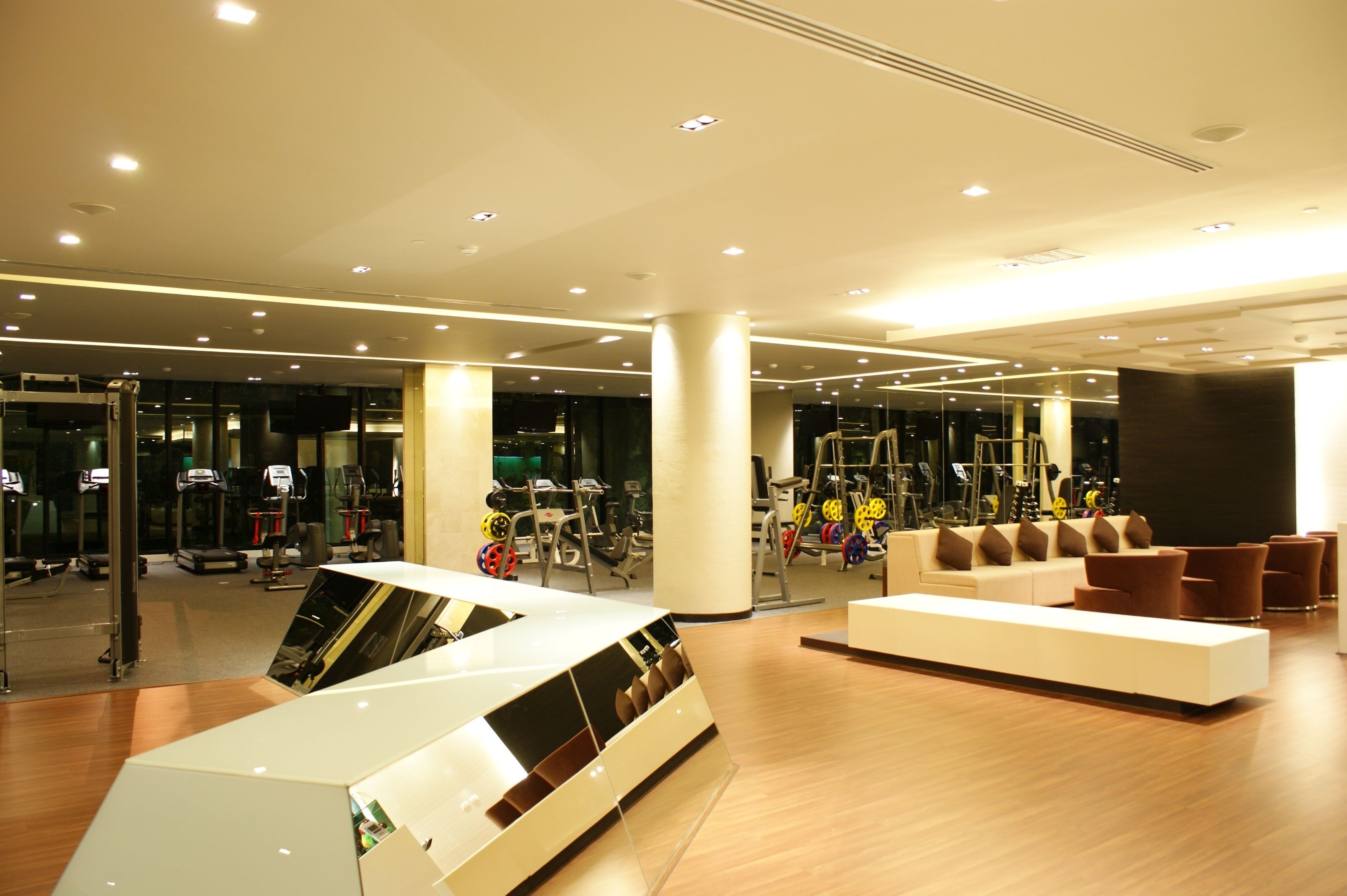 A modern gym with exercise equipment, a reception desk, and a seating area.