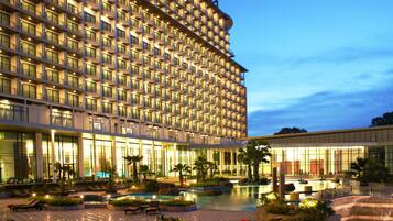 A large hotel with multiple floors, a swimming pool, and outdoor seating areas.