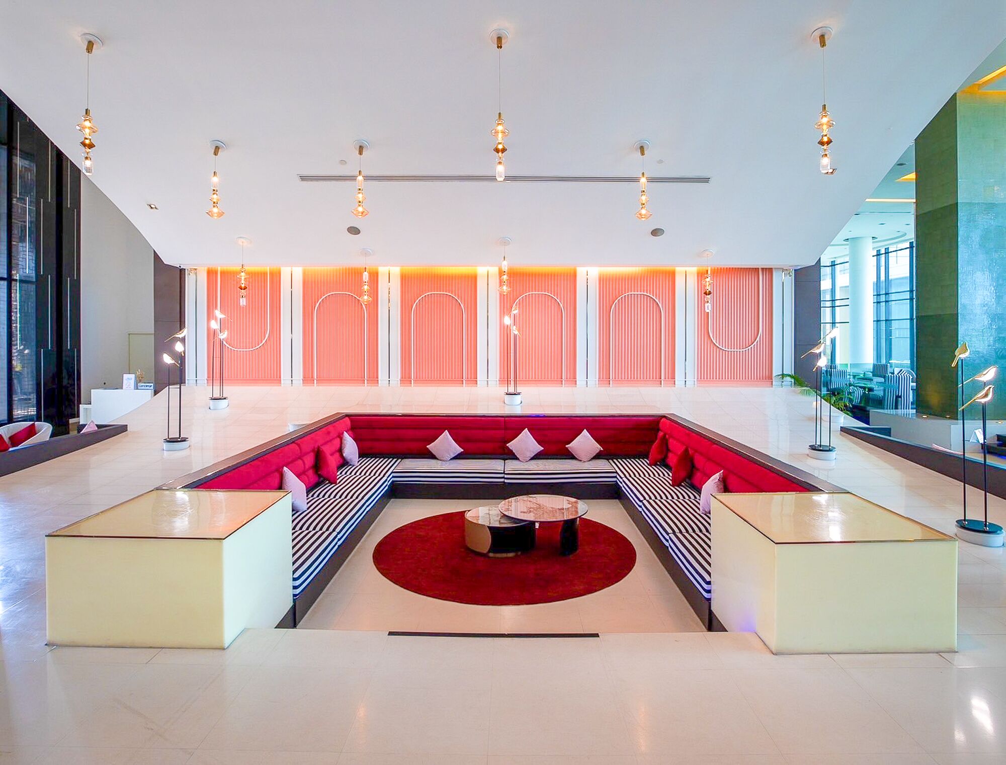 Eine moderne Lobby mit einer zentralen Sitzecke, einem Empfangsbereich und einem großen Fenster mit Blick ins Freie.