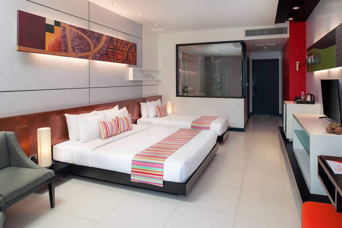 A modern hotel room with a large bed, a desk, and a shower area.