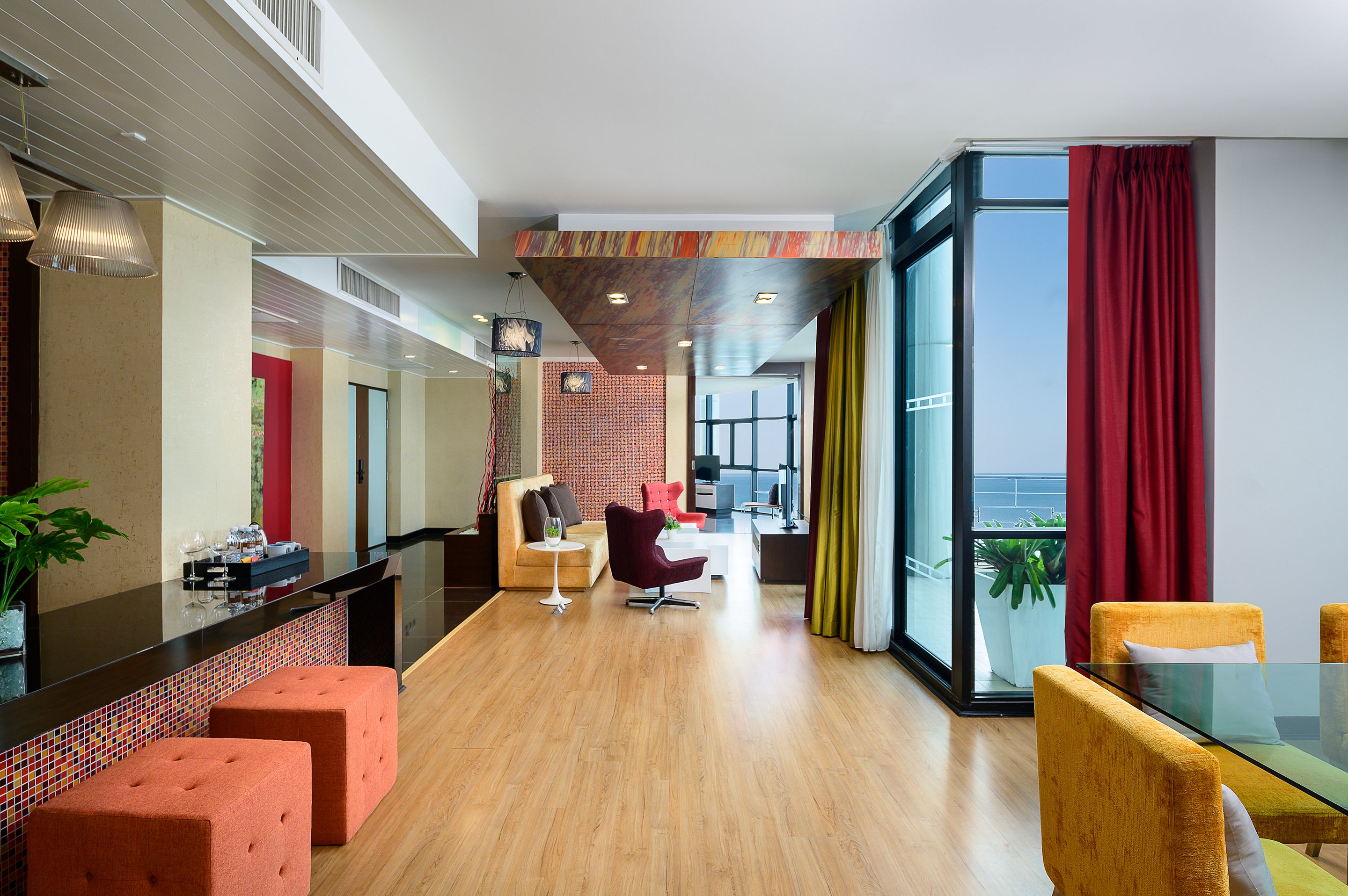 Eine moderne Hotelhalle mit Holzboden, einer Rezeption und einer Sitzecke mit orangefarbenen und gelben Stühlen.