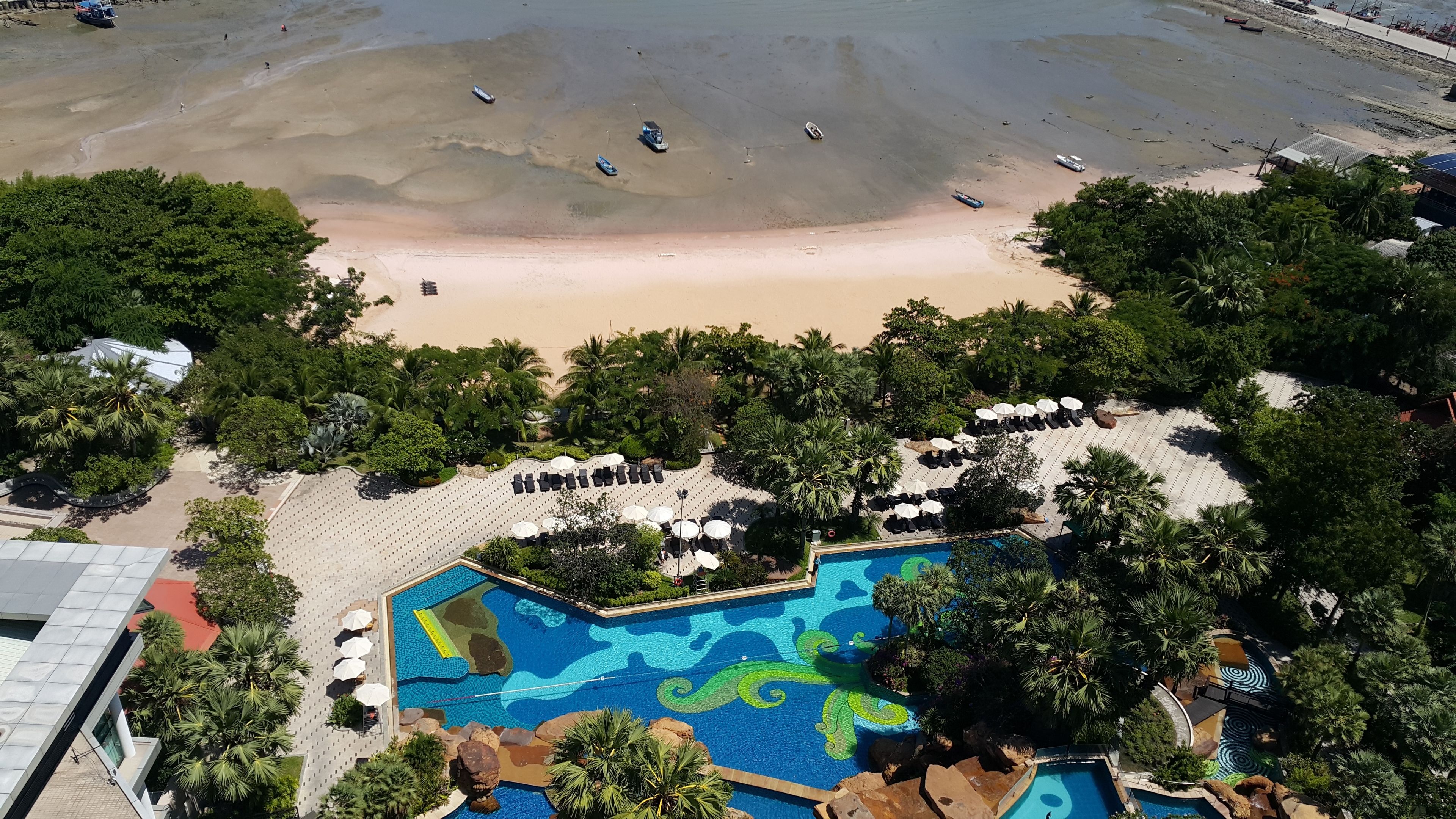 Ein Resort mit Schwimmbad, Strand und Palmen.