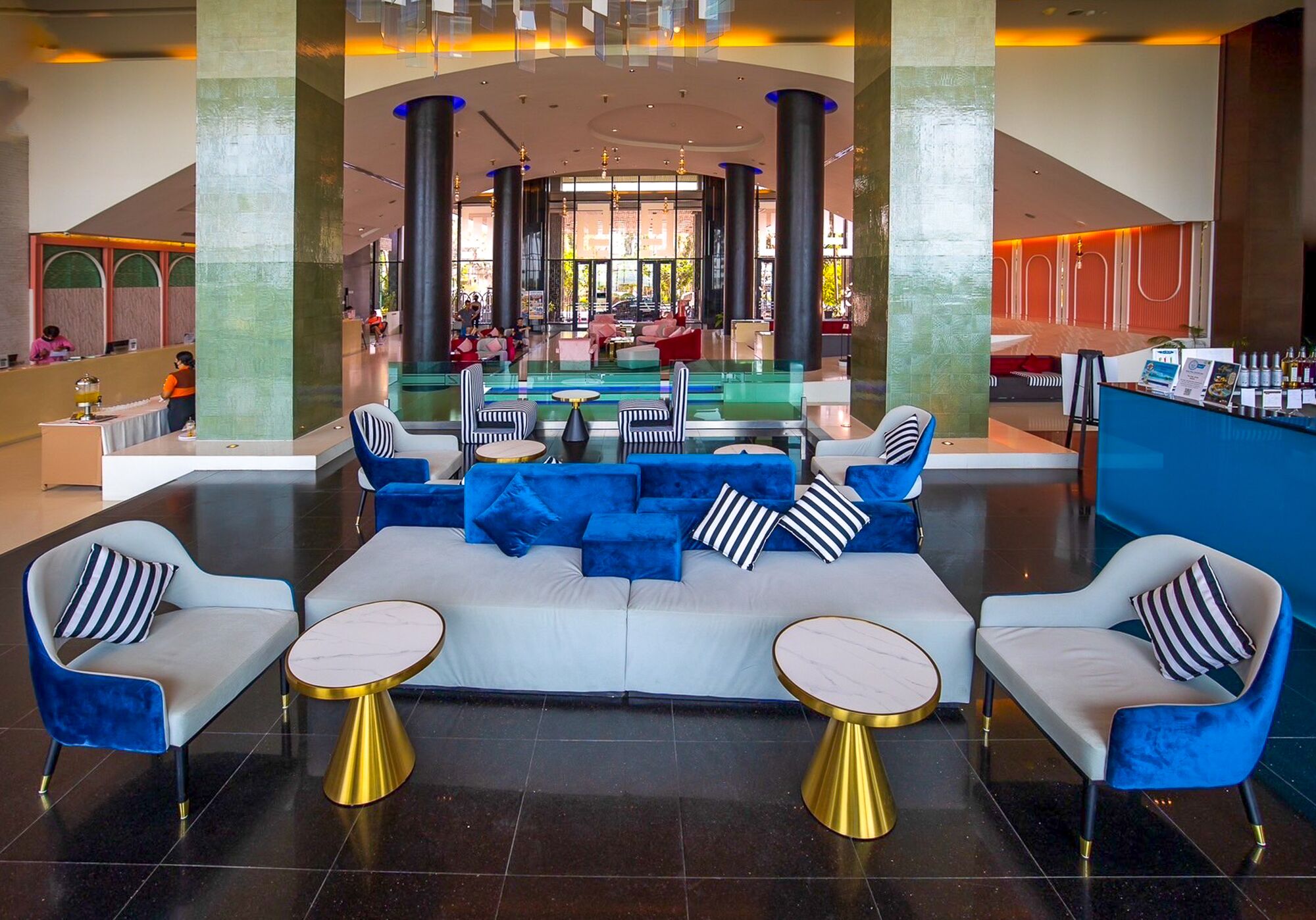 A spacious lobby with a central seating area featuring sofas and armchairs, a reception desk, and a view of the interior.