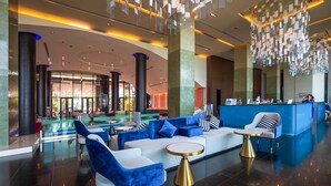 A modern lobby with a reception desk, seating area with sofas and armchairs, and a glass partition. - The Zign Hotel (Pattaya)
