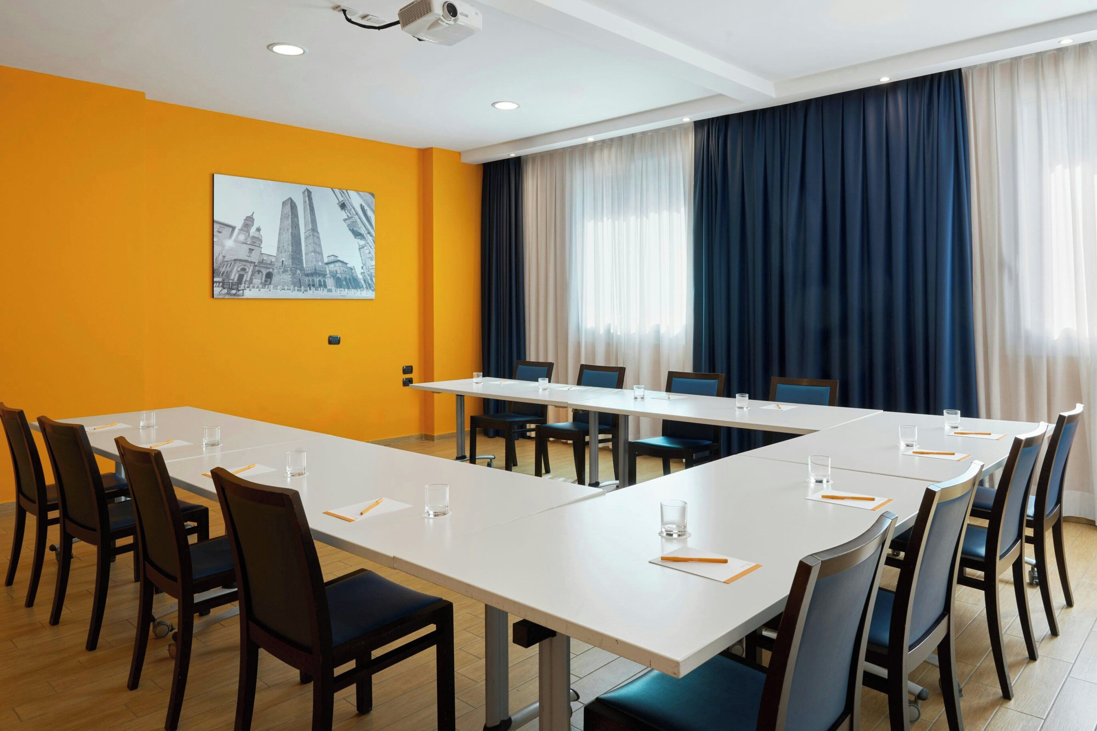 A conference room with a long table, chairs, and a projector on the ceiling.