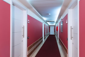 A long, narrow hallway with red walls and white doors, leading to a series of rooms. - Four Points Flex by Sheraton Bologna Airport (Bologna)