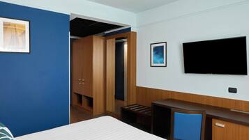 Una habitación de hotel con cama, escritorio, televisor y armario.