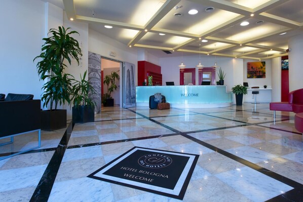 A hotel lobby with a reception desk, seating area, and a check-in counter. - Four Points Flex by Sheraton Bologna Airport (Bologna)