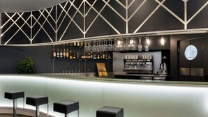 Zona de bar moderna con una barra curva, taburetes, una vinoteca y una máquina de café.