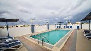 Una piscina en la azotea con sillones de descanso, una piscina y vistas de la ciudad.