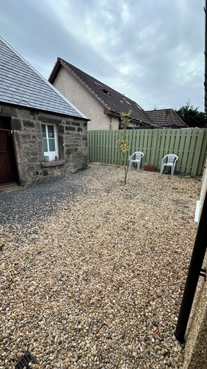 A stone building with a sloped roof, a gravel driveway, and a wooden fence. - Aynetree Guest House (Edinburgh)