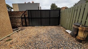 A gravel driveway leading to a black gate, surrounded by a stone wall and a wooden fence. - Aynetree Guest House (Edinburgh)