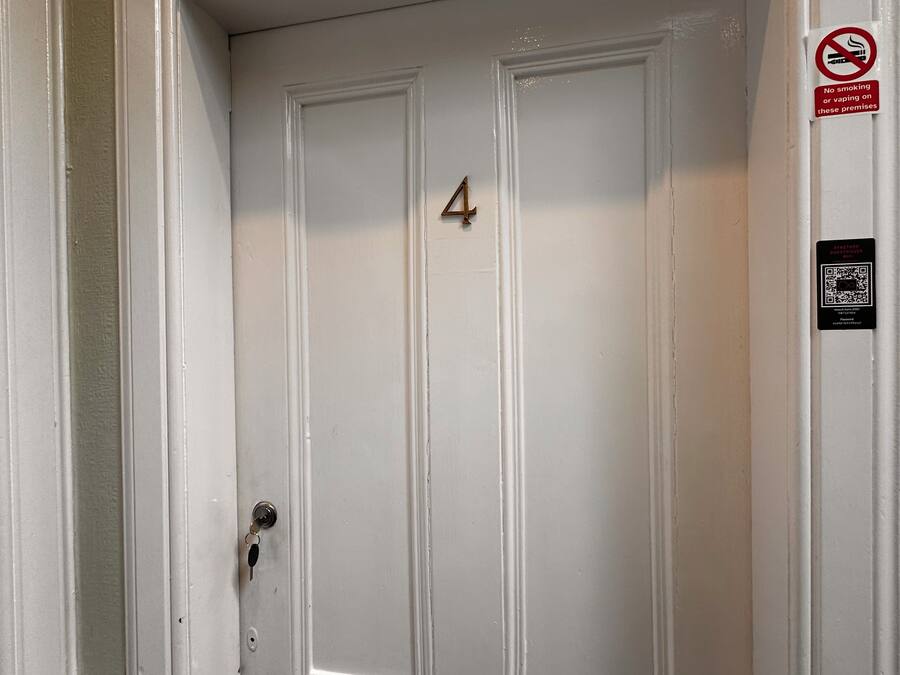 A white door with the number 4, a no-smoking sign, and a QR code for guesthouse information.