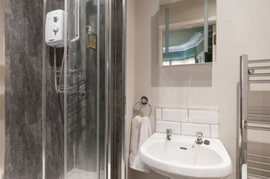 A bathroom with a glass-enclosed shower, a white sink, and a towel rack.