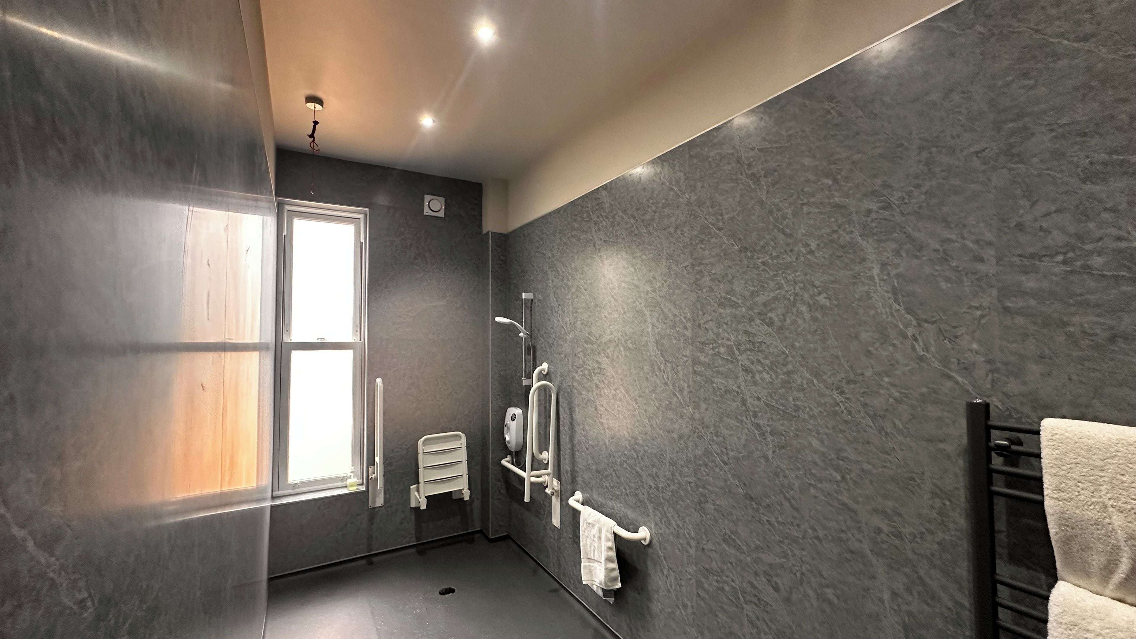 A modern bathroom with a large window, a towel rack, and a shower area.