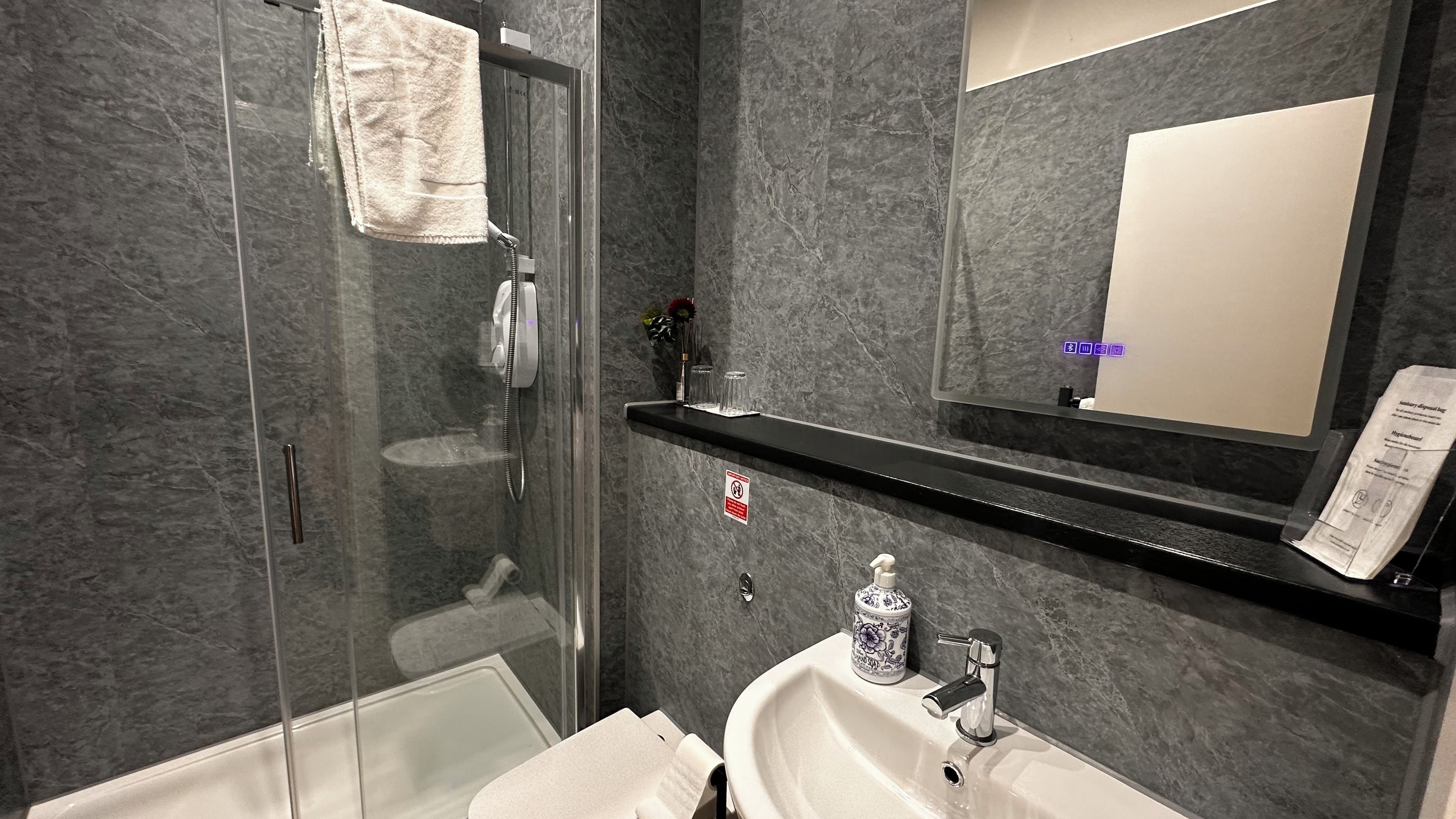 A modern bathroom with a glass-enclosed shower, a white sink, and a mirror above the sink.