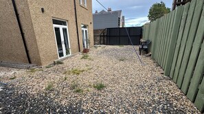 A gravel driveway leading to a house with a wooden fence and a metal gate. - Aynetree Guest House (Edinburgh)