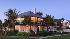 A two-story house with a balcony, surrounded by palm trees and well-maintained landscaping. - Port d'Hiver (Melbourne Beach)
