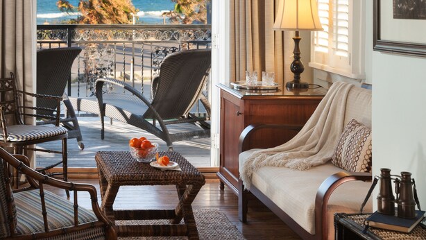 A cozy room with a wooden ceiling, a balcony with ocean views, wicker furniture, and a table with oranges. - Port d'Hiver (Melbourne Beach)