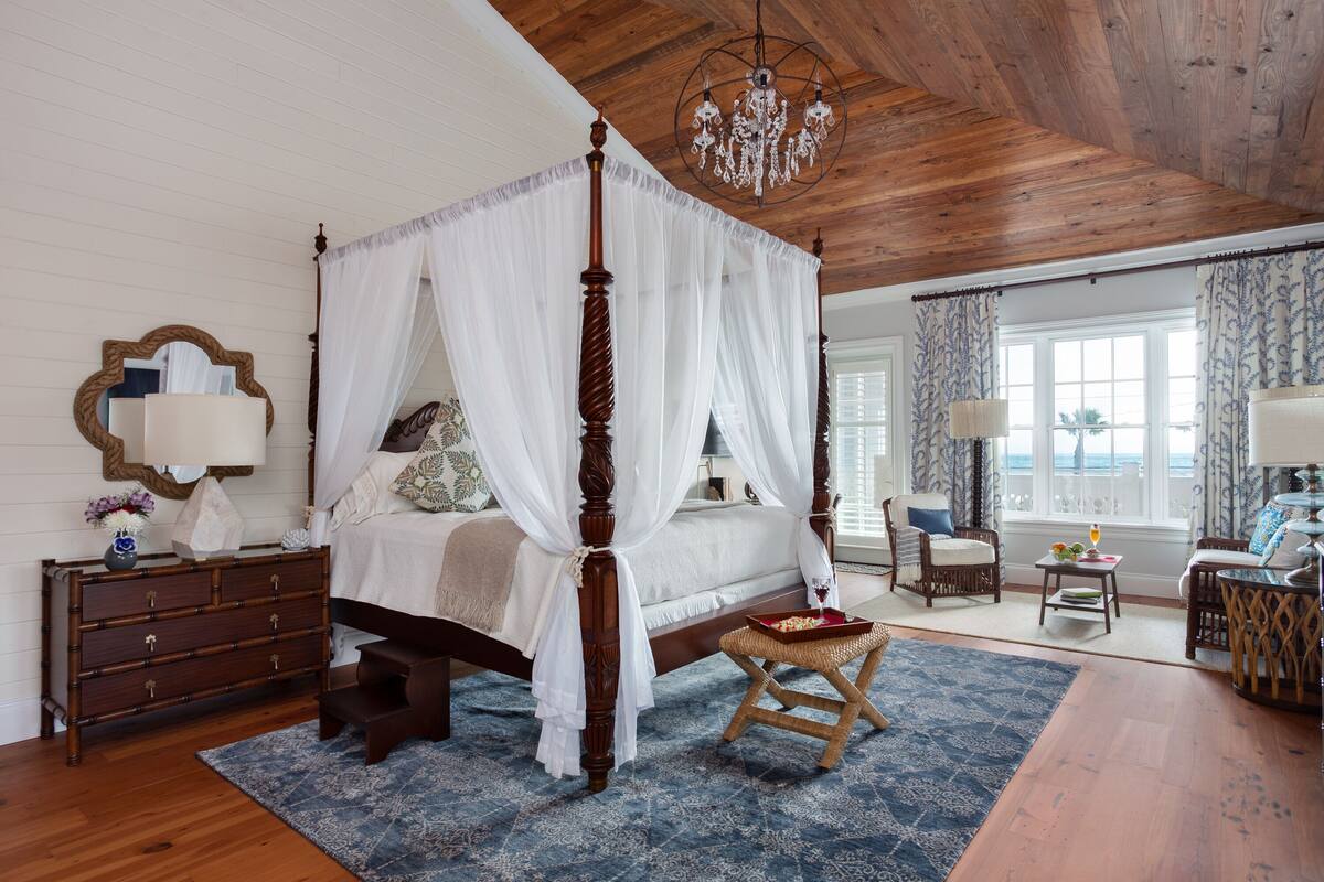 A bedroom with a four-poster bed, wooden ceiling, and a chandelier.