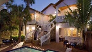 A pool area with a stone staircase and white railings, surrounded by palm trees and outdoor furniture. - Port d'Hiver (Melbourne Beach)