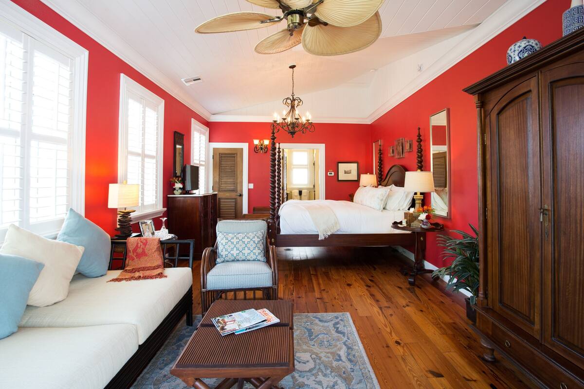 A bedroom with a bed, a chair, a table, and a wardrobe.
